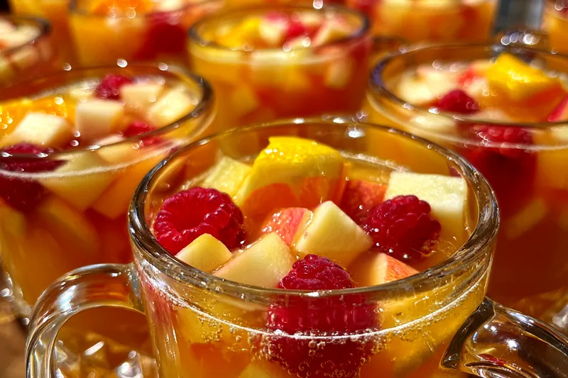 A colorful array of ingredients for Festive Thanksgiving Punch including apples, oranges, and spices.